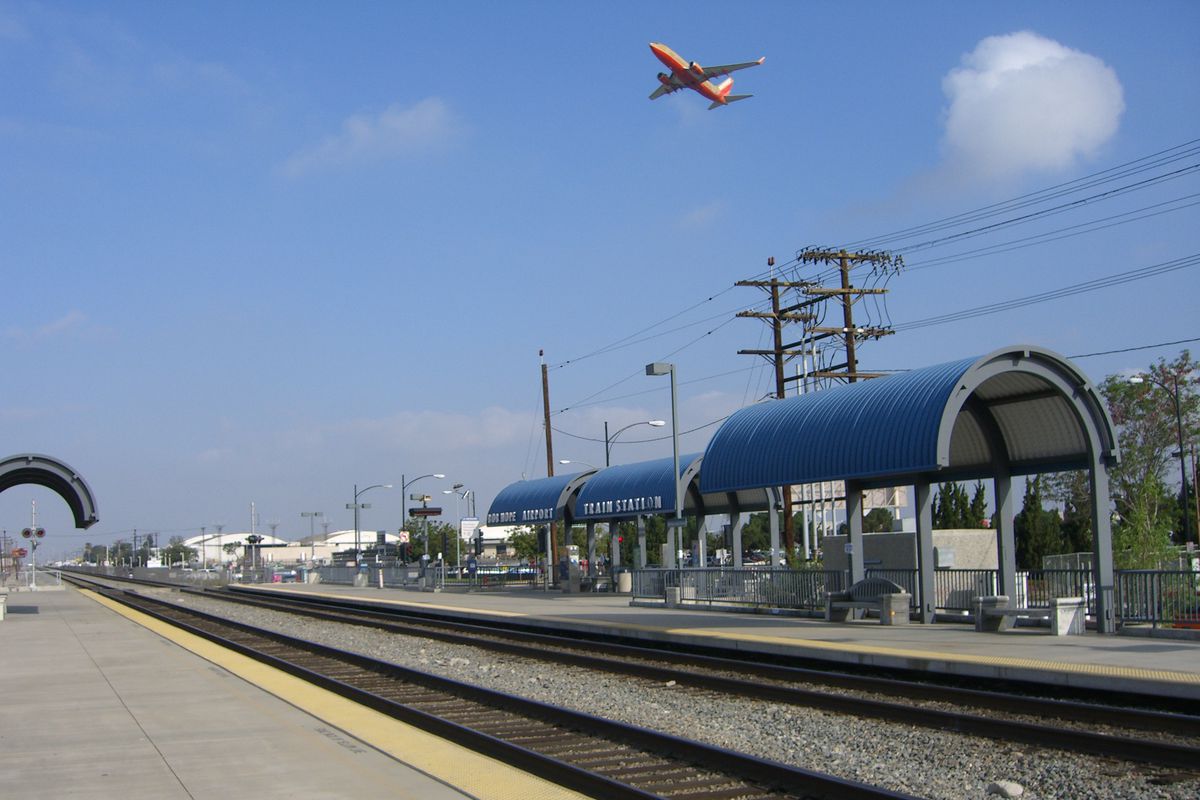 A plane flying over the Burbank Airport train station. 