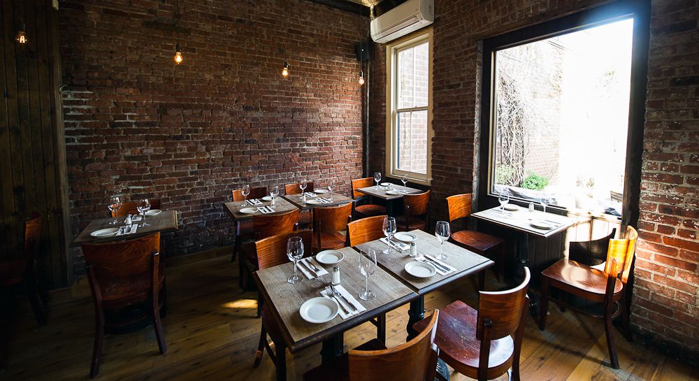 A brick-lined dining room with a window to the right.