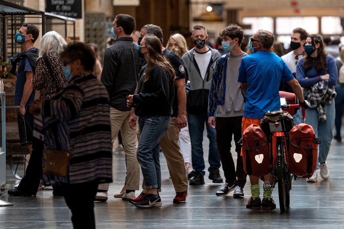 Visitors to the Ferry Building in San Francisco wear masks as they walk around indoors.