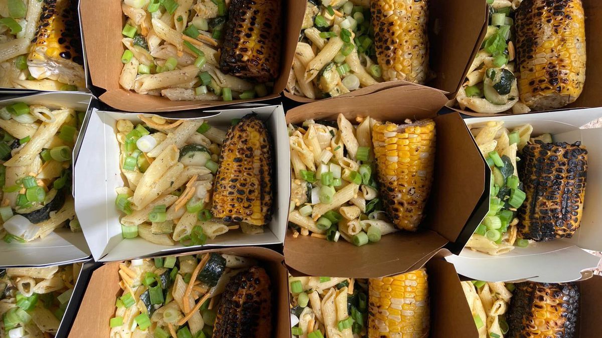 Various takeout containers full of pastas and corn.