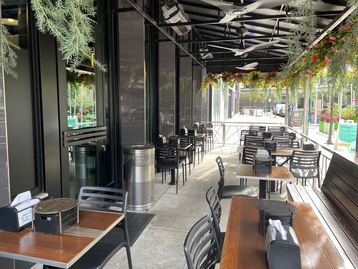 Black seats with wood dining tables, hanging plants under a black awning