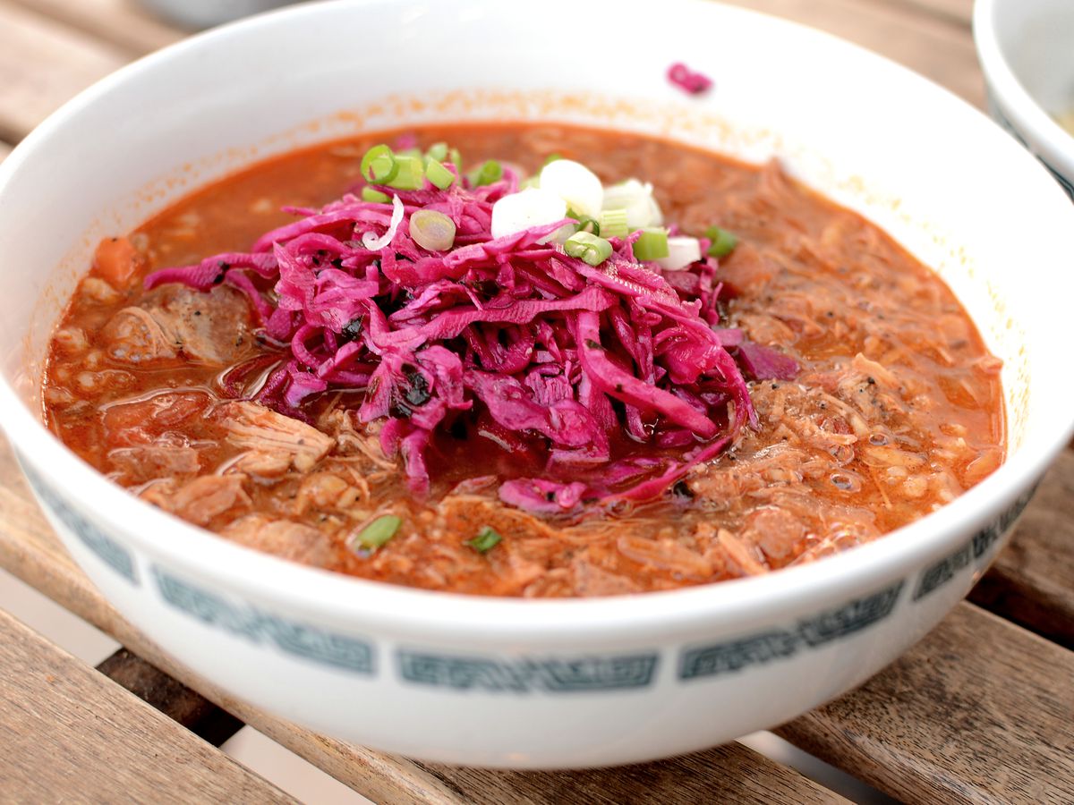 A bowl of Romanian soup topped with red cabbage.