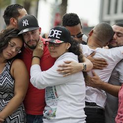 Mourners console each other as they grieve the loss of their friends Amanda Alvear and Mercedez Flores who were killed in the mass shooting at the Pulse nightclub, as they visit a makeshift memorial downtown, Monday, June 13, 2016, in Orlando, Fla. A gunman killed dozens of people in a massacre at a crowded gay nightclub in Orlando on Sunday, making it the deadliest mass shooting in modern U.S. history. 