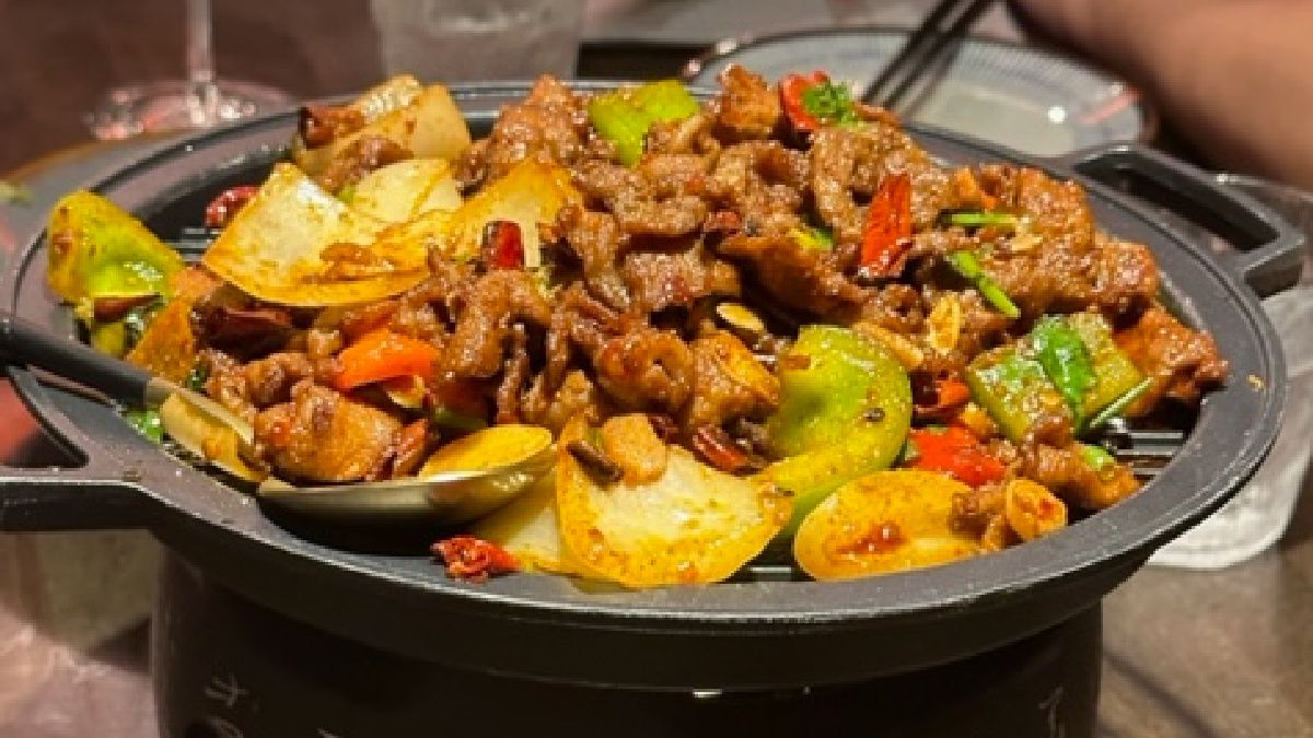 Beef, peppers, onion, and other items in a dry hotpot.