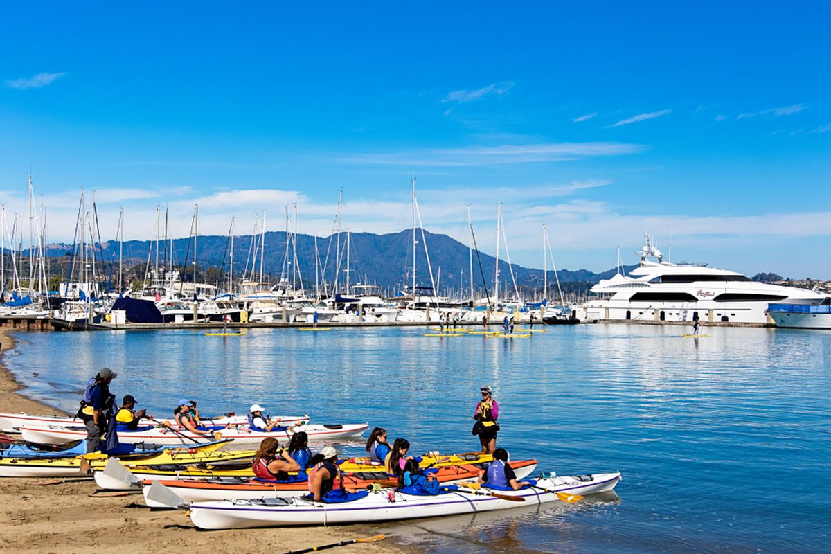 Boats parked at the marina in Richardson Bay, with kayaks on the beach in the foreground.