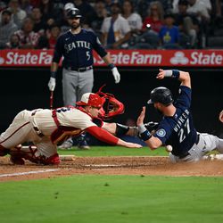 ANAHEIM, CA - SEPTEMBER 16: Los Angeles Angels catcher Max Stassi (33) can’t hold onto the ball allowing Seattle Mariners left fielder Jesse Winker (27) to be safe at the plate in the sixth inning of an MLB baseball game played on September 16, 2022 at Angel Stadium in Anaheim, CA.