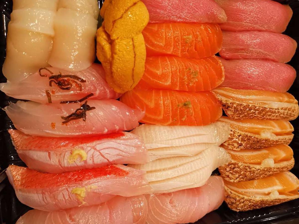 A takeout box full of colorful nigiri sushi —&nbsp;red, pink, orange, white