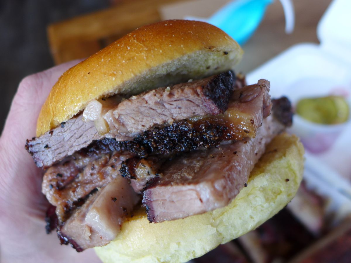 Thickly stacked barbecued brisket overflows from a small bun.