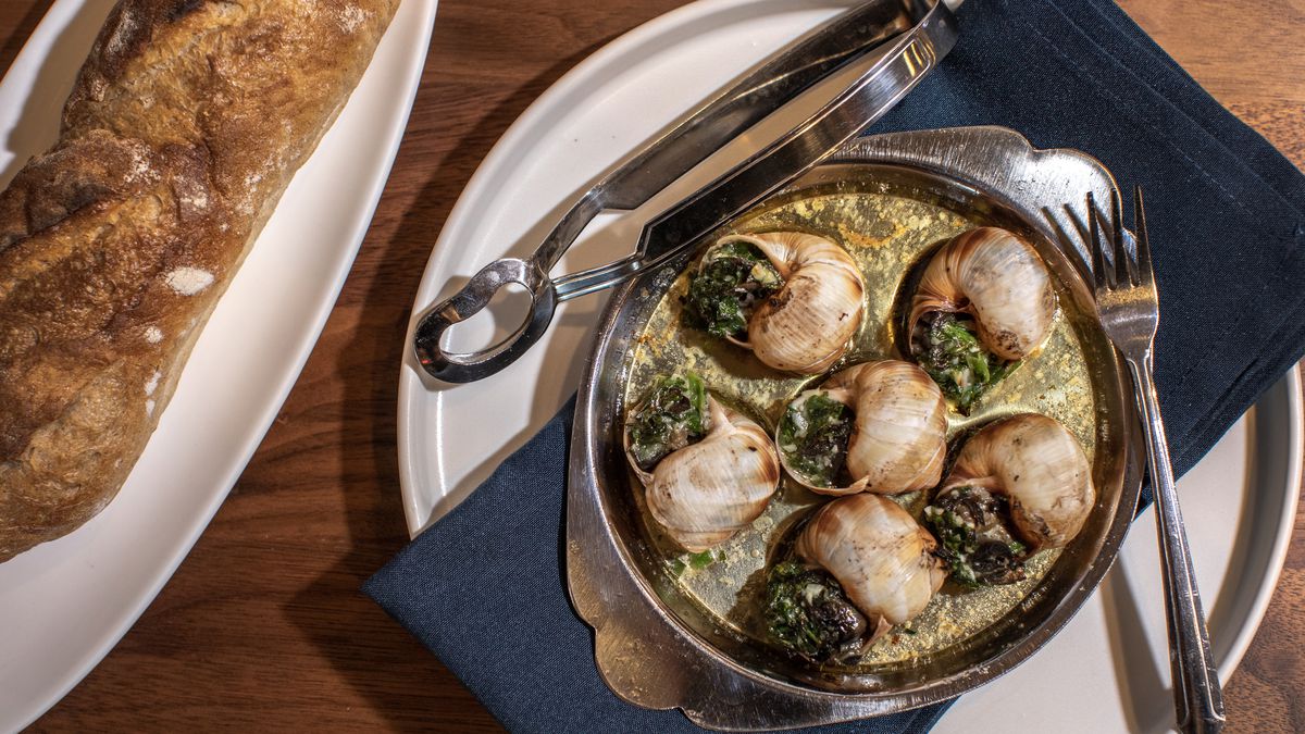A classic dish of French escargot swimming in garlic herb butter served with a demi baguette from Foundation Social Eatery in Alpharetta, GA.