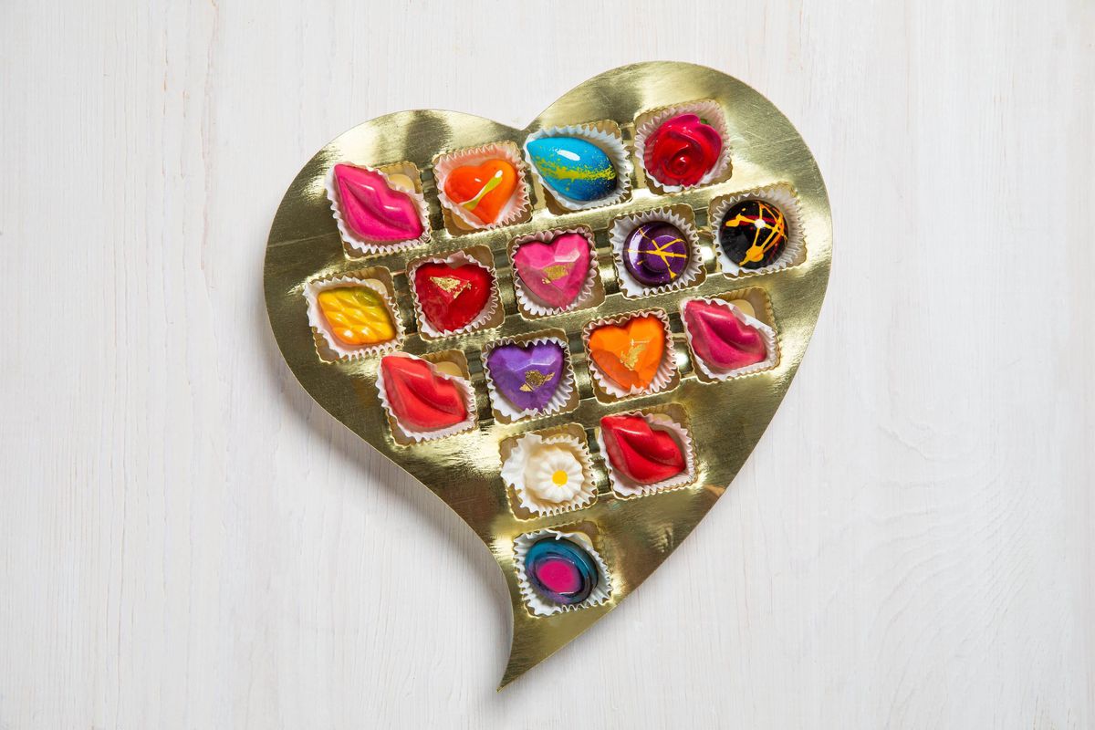 A golden heart box filled with bonbons shaped like hearts and lips