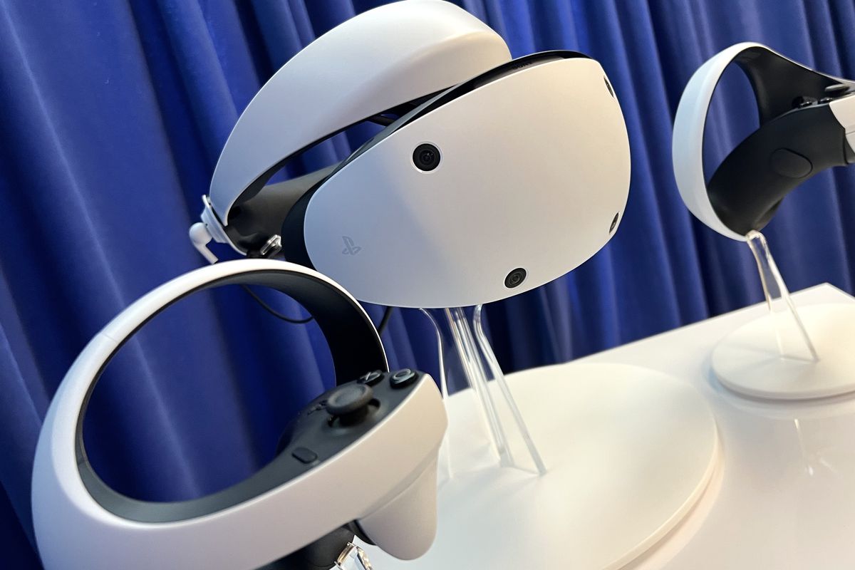 Sony’s PlayStation VR2 headset sits on a podium alongside two PlayStation VR2 Sense controllers