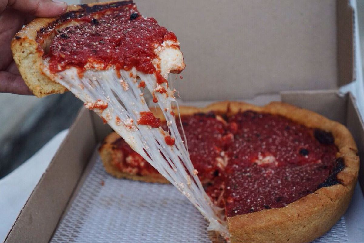 A cheesy slice of deep dish pizza being pulled out of the box at Dough Box in Los Angeles.