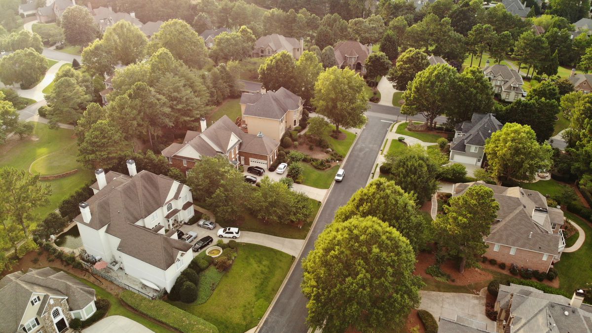 Aerial view of a residential neighborhood, large homes surrounded by big green trees and yards. 