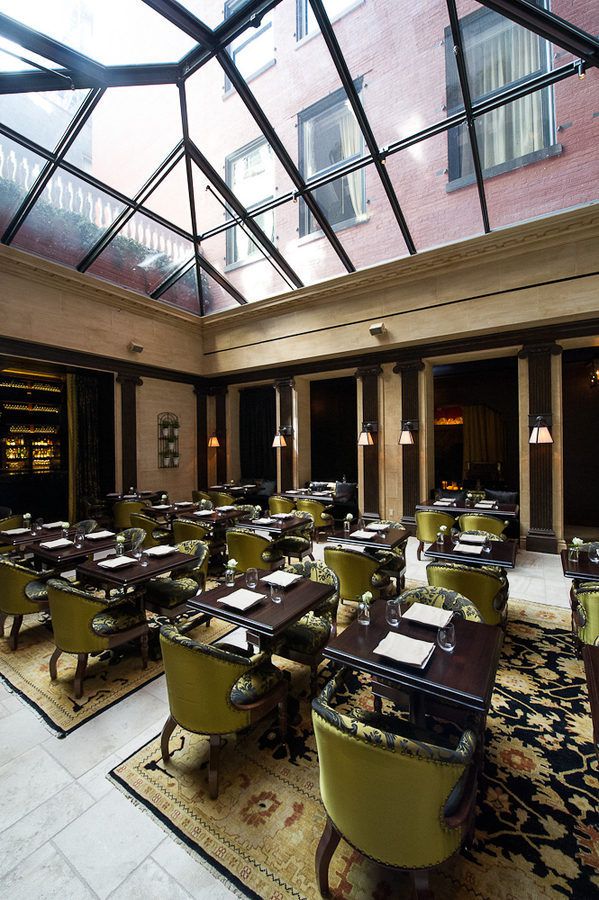 The NoMad Restaurant’s dining room has a high glass ceiling and dark brown tables