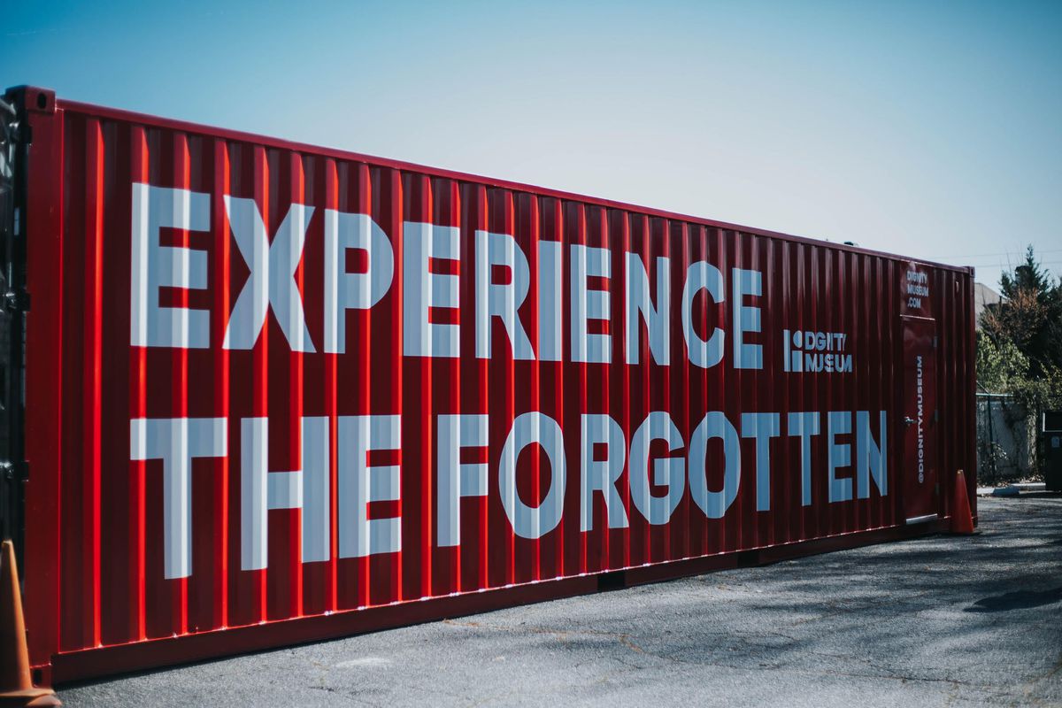 A red shipping crate is adorned with white letters reading “Experience the Forgotten.”