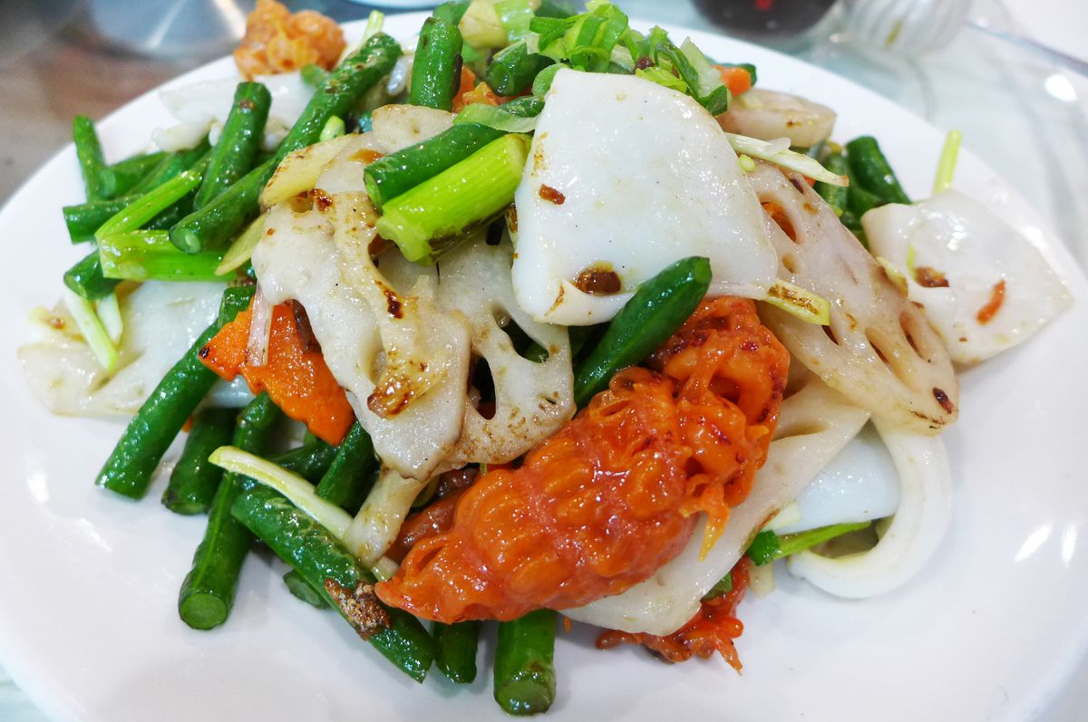 White cuttlefish and red sea cucumber sit in a heap of lotus root and green beans...