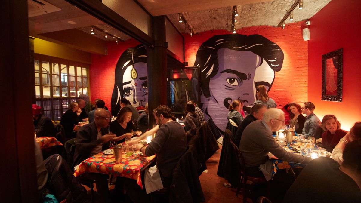 Bombay Bread Bar’s dining room, with red walls and a mural of people in the back.