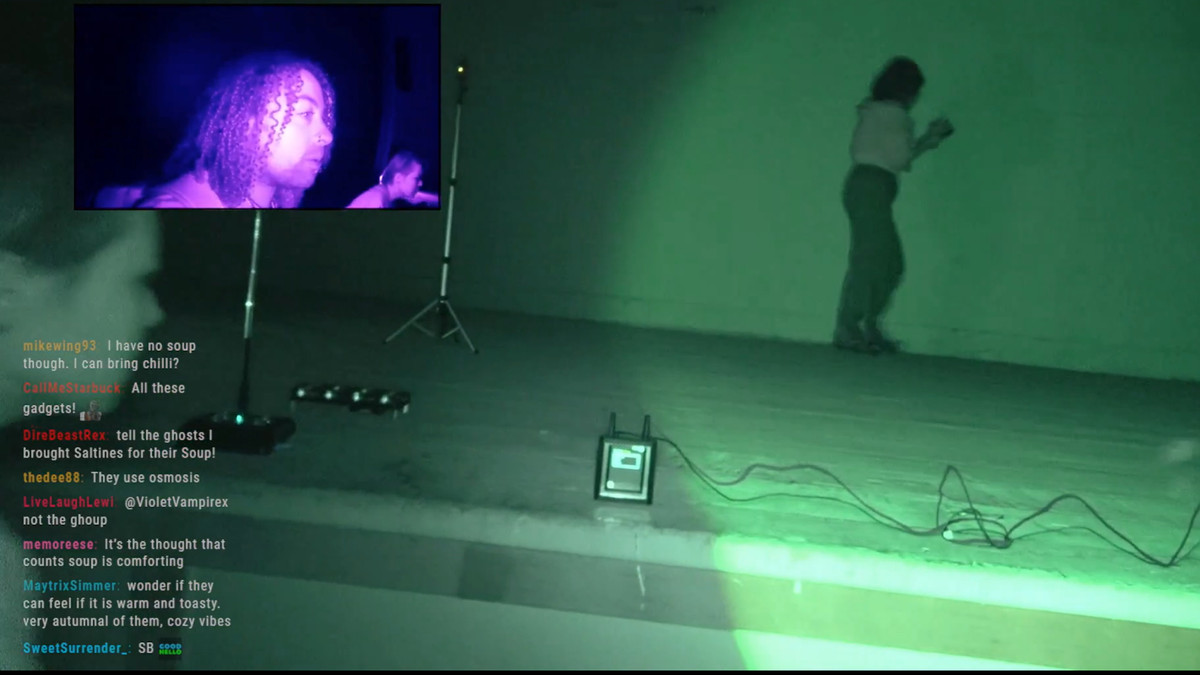 A live feed from a ghost hunting Twitch stream, showing a picture in picture of a person’s face and a green lit stage.