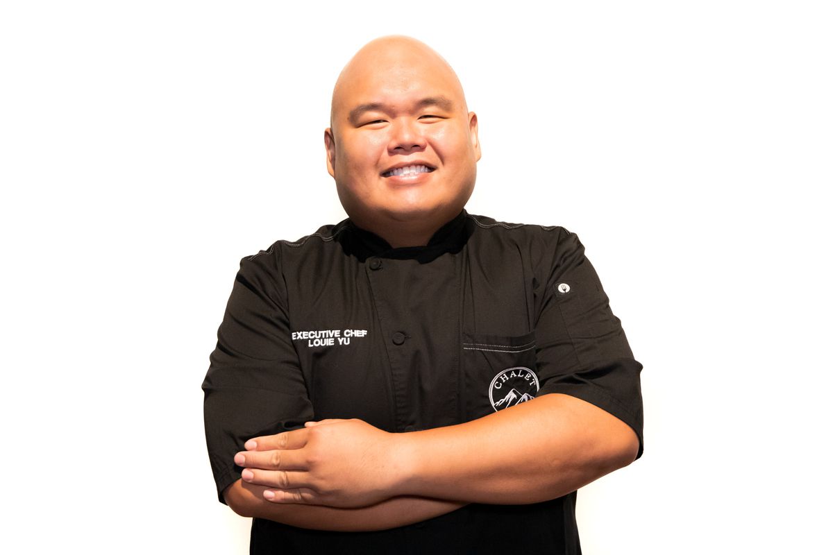 A man in a black chef’s jacket smiling