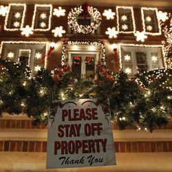 In this Dec. 14, 2016, photo, a sign in front of a decorated house warns visitors to keep off the premises in the Dyker Heights neighborhood of New York. While many residents welcome the crowds that flock to the area to see over-the-top Christmas decorations on private homes, not all residents are happy with the hordes of tourists. 