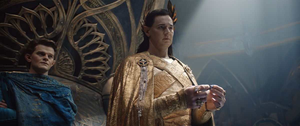 Gil-galad (Benjamin Walker) standing and holding mithril, with Elrond (Robert Aramayo) looking over his shoulder