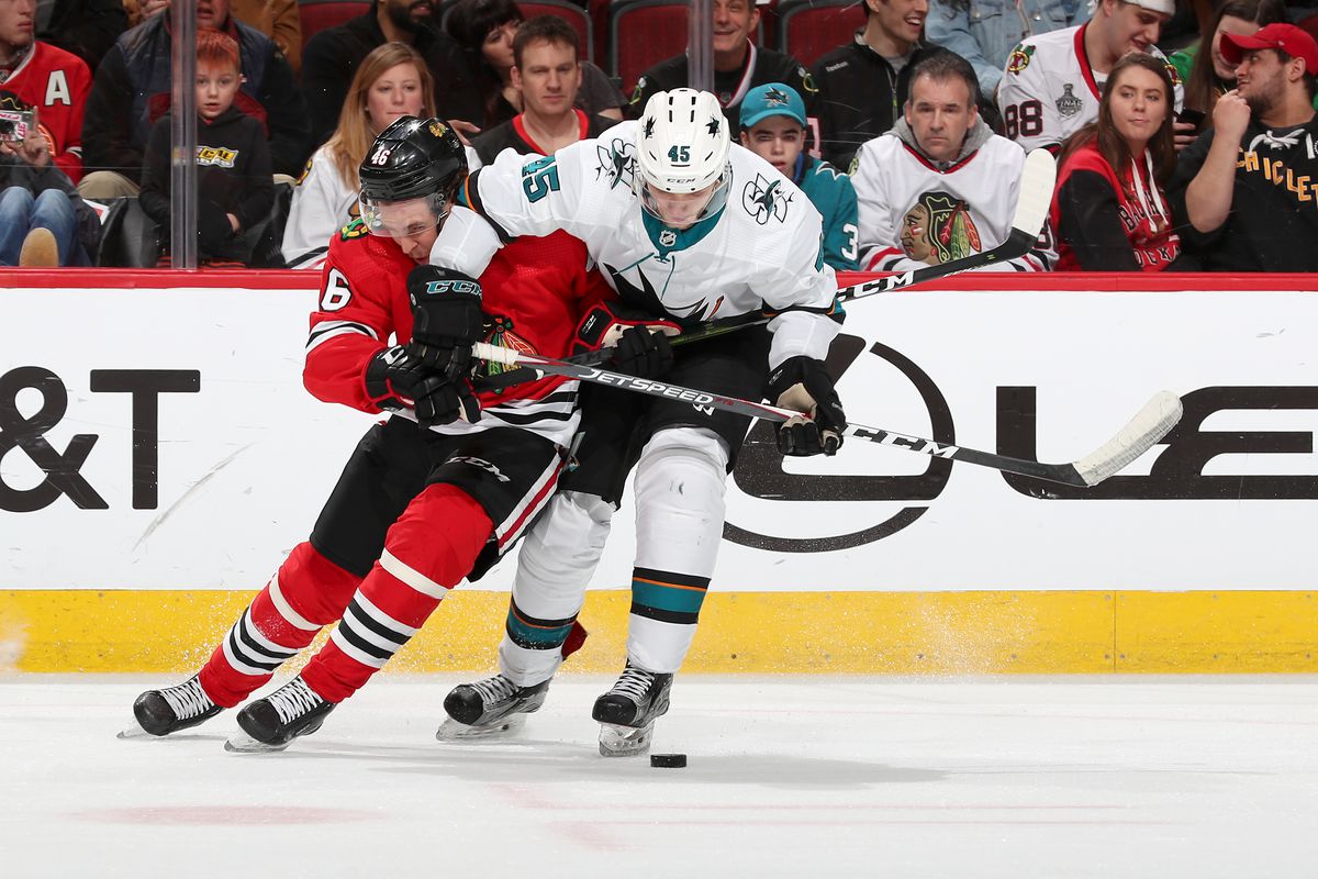 Lucas Carlsson #46 of the Chicago Blackhawks and Lean Bergmann #45 of the San Jose Sharks battle for the puck in the third period at the United Center on March 11, 2020 in Chicago, Illinois.