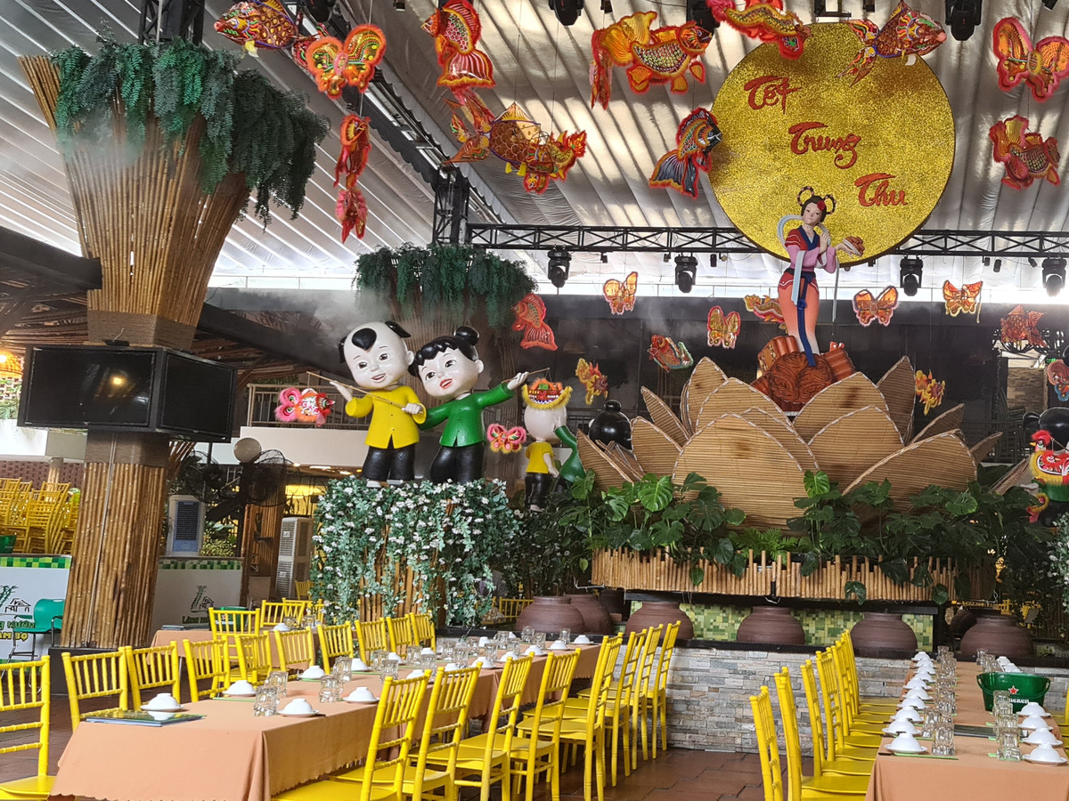 A fanciful restaurant interior with large statues of cartoonish children, fake foliage, and decorations hanging from the high ceiling. 