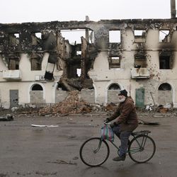 A resident rides his bicycle past a destroyed building in the town of Vuhlehirsk, Ukraine, Friday, Feb. 6, 2015. German Chancellor Angela Merkel and French President Francois Holland are set to hold talks with Russian President Vladimir Putin in the Kremlin on Friday, one day after discussing peace proposals for Ukraine's conflict with Ukrainian President Petro Poroshenko. 