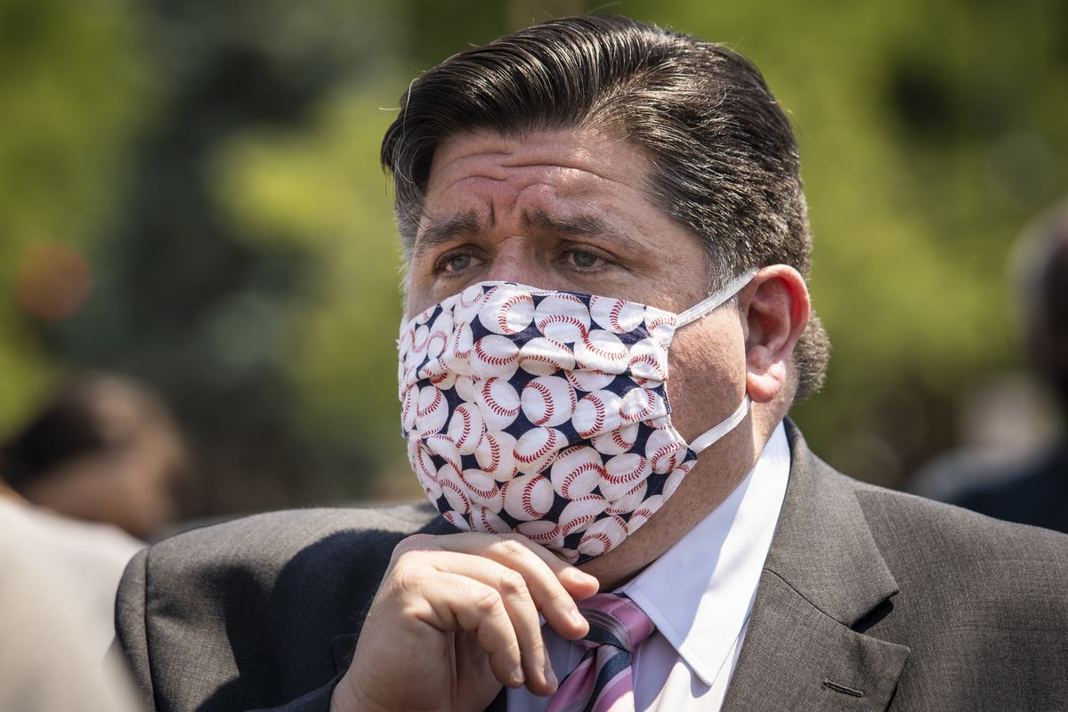 Gov. J.B. Pritzker adjusts his face mask after a news conference in June 2020.