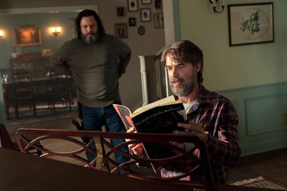 Bill (Nick Offerman) stands awkwardly as Frank (Murray Bartlett) cheerfully pages through book of Linda Rondstadt sheet music, seated at a piano in The Last of Us.