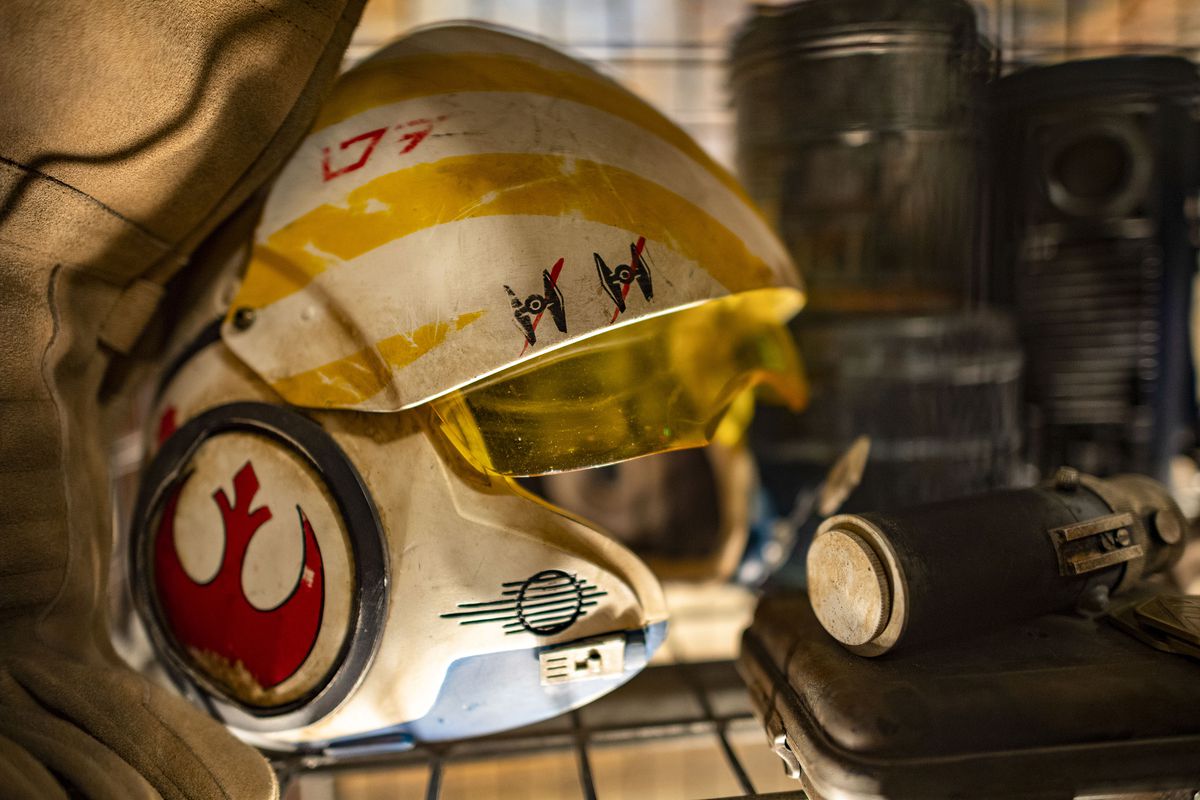 a resistance helmet sits next to a lightsaber in the queue for Rise of the Resistance