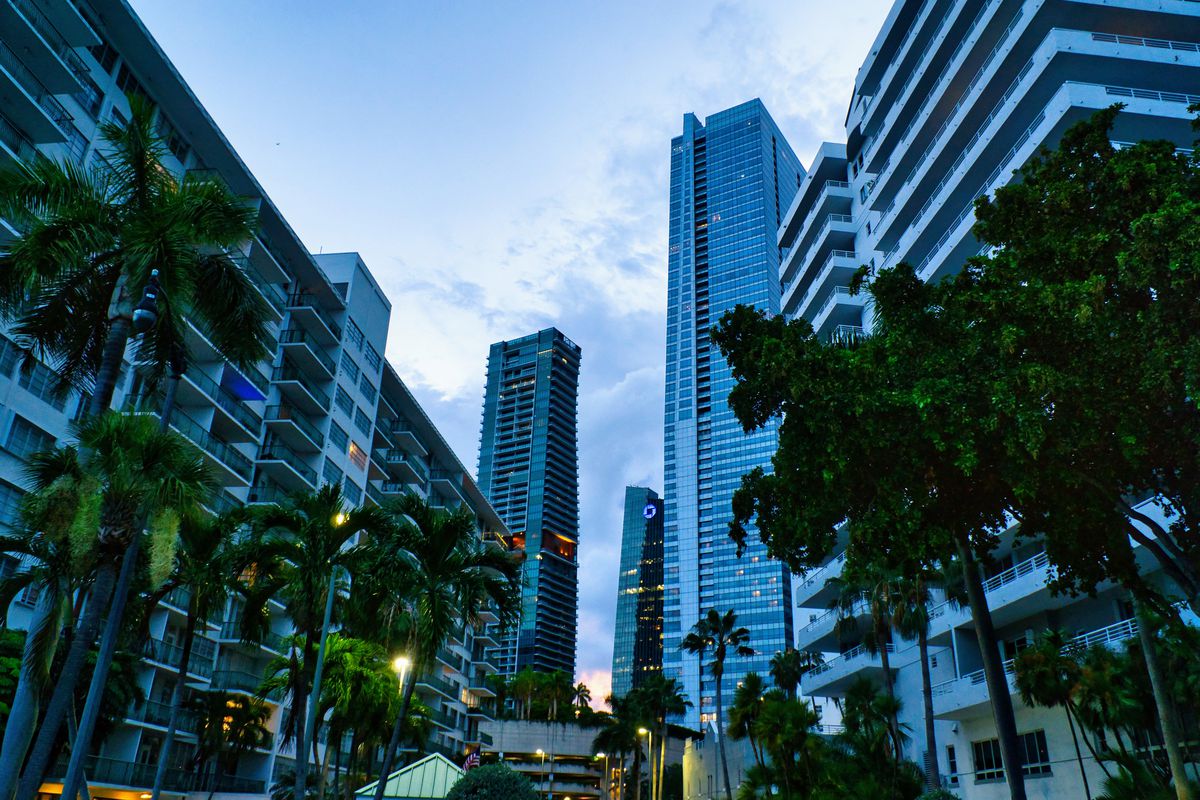 Steel-and-glass skyscrapers are flanked by palm trees as the sun goes down in Miami’s Brickell high-rise neighborhood.