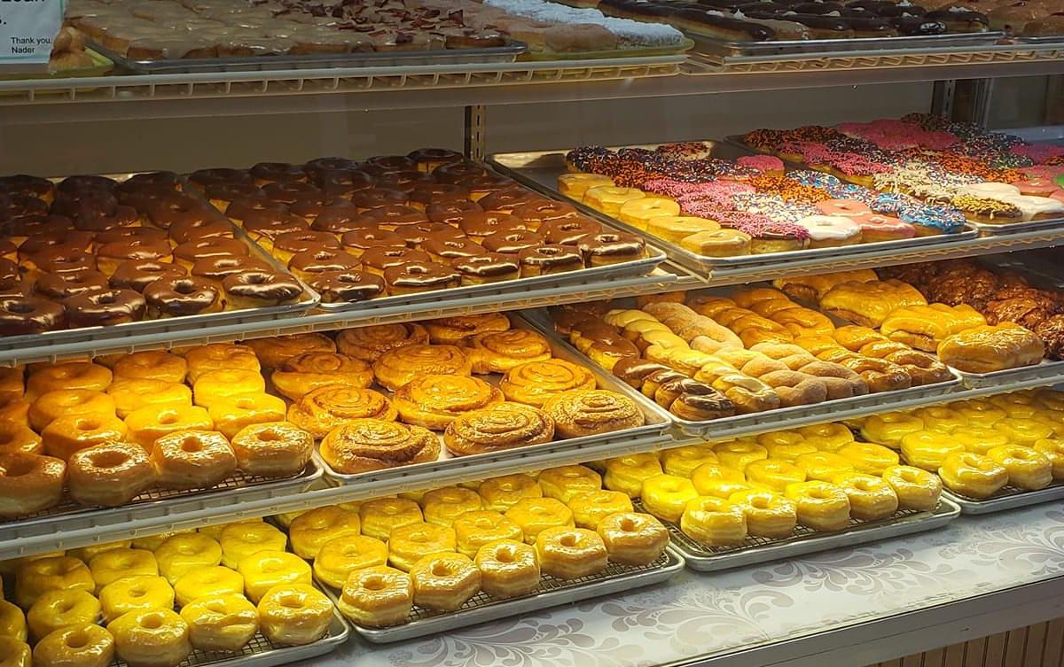 Four rows filled with trays of assorted doughnuts