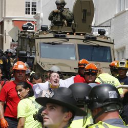 Rescue personnel help injured people after a car ran into a large group of protesters after an white nationalist rally in Charlottesville, Va., Saturday, Aug. 12, 2017. The nationalists were holding the rally to protest plans by the city of Charlottesville to remove a statue of Confederate Gen. Robert E. Lee. There were several hundred protesters marching in a long line when the car drove into a group of them. 