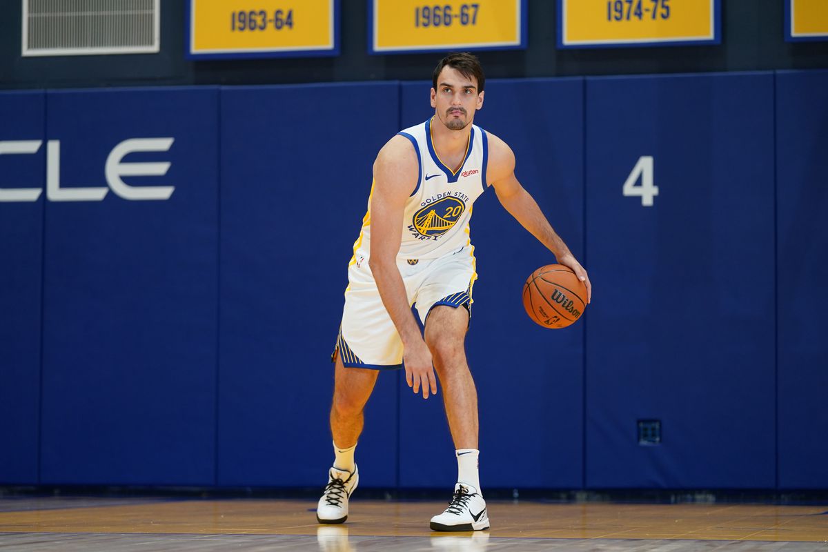 Golden State Warriors forward Dario Saric (20) dribbles the ball during Media Day at the Chase Center. A couple of the Warriors’ Championship banners hang on the wall behind him.