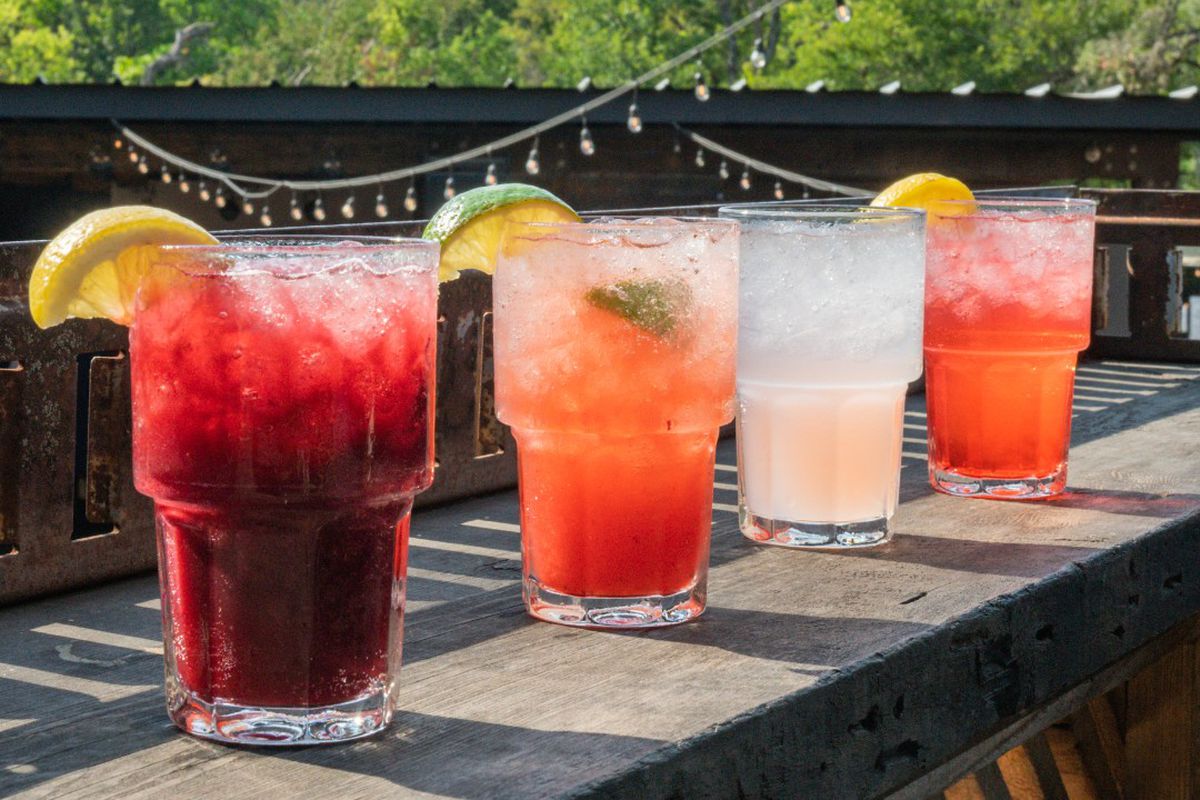 Drinks on a railing on an outdoor wooden patio.