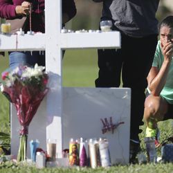 Maria Creed is overcome with emotion as she crouches in front of one of the memorial crosses at Pine Trails Park in Parkland, Fla., Friday, Feb. 16, 2018, that were placed for the victims of the Wednesday shooting at Marjory Stoneman Douglas High School. Creed's son, Michael Creed, is a sophomore at the school. (Amy Beth Bennett/South Florida Sun-Sentinel via AP)
