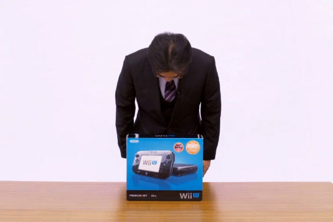 Satoru Iwata bowing over a Wii U box
