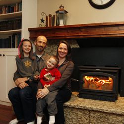 Timothy and Esther Olschewski and two of their six children, Jordan, 9, and Moroni, 3, gather around their Lennox Perform C210 Phase II EPA-certified wood-burning stove in their home in West Valley City Thursday, Jan. 8, 2015. The stove has a two-tier burning system that emits cleaner fumes. 