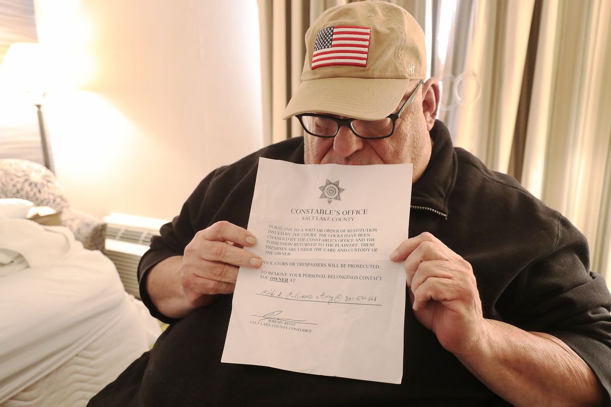 Doug Henderson holds an eviction notice in his and his wife’s room at the Salt Lake Plaza Hotel Temple Square in Salt Lake City on Friday, Jan. 15, 2021.&nbsp;The Hendersons were evicted from their apartment earlier in the week.