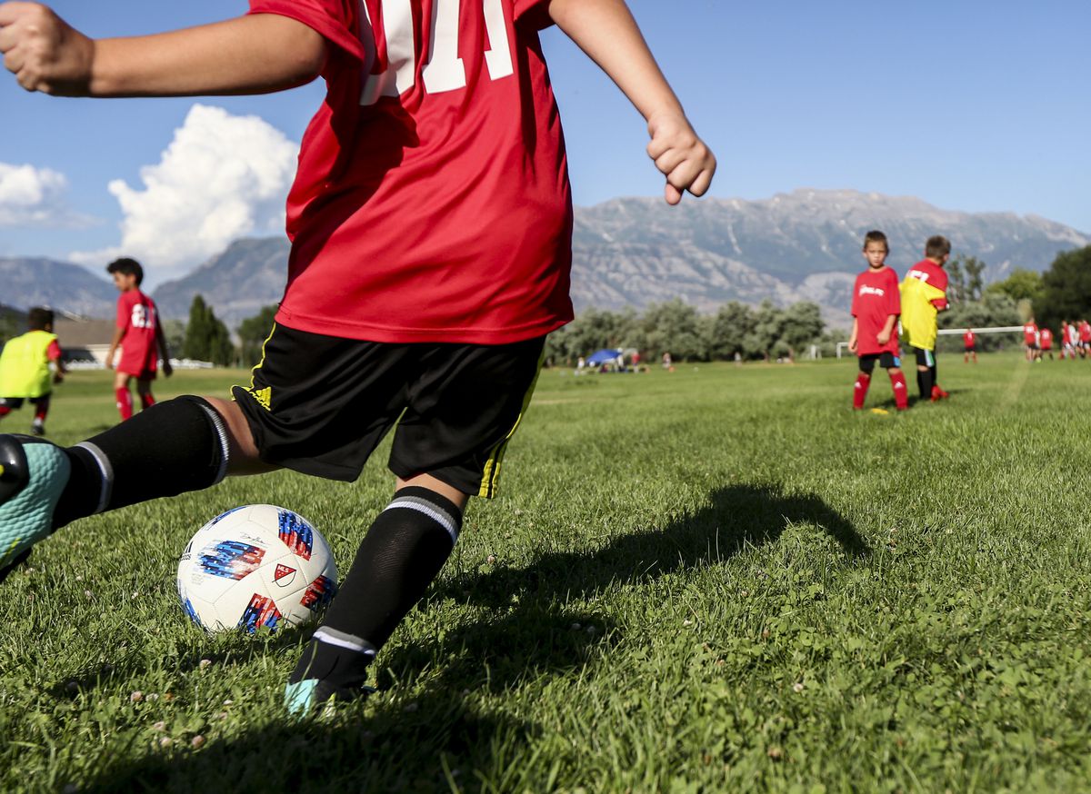 A youth soccer player kicks the ball to teammates during a drill in a practice at North Lake Park in Lehi on Thursday, Aug. 1, 2019.