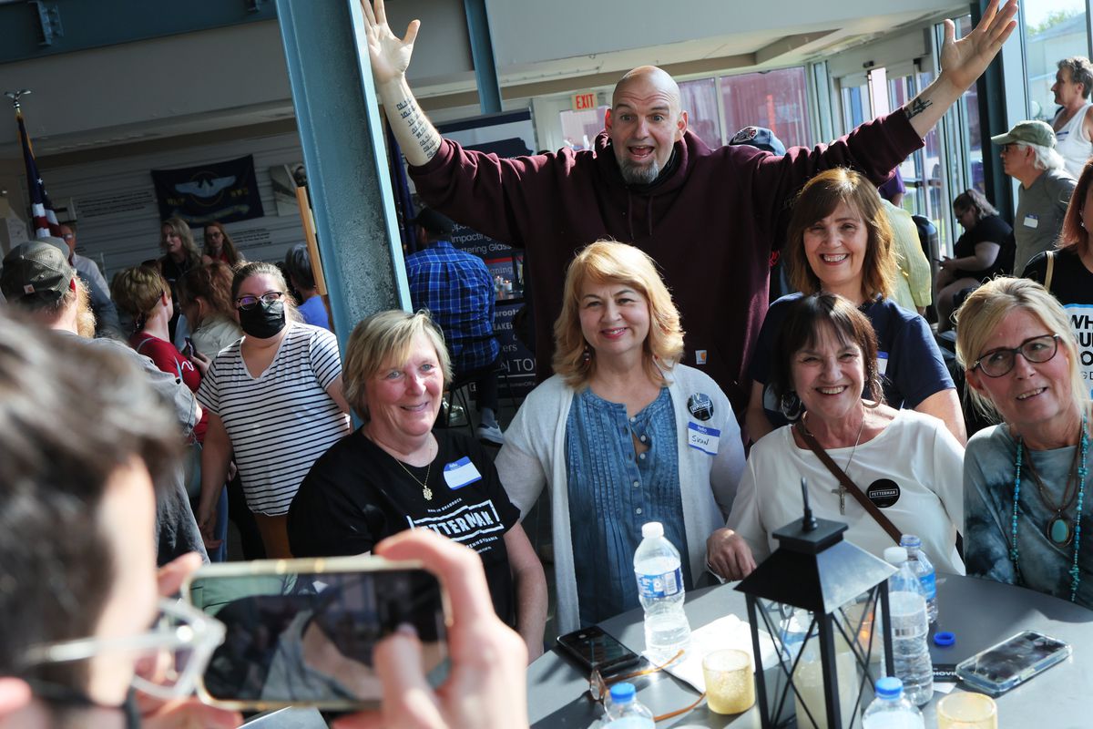 Pennsylvania Lt. Gov. John Fetterman raises his hands behind a group of women posing for a photo on the campaign trail.