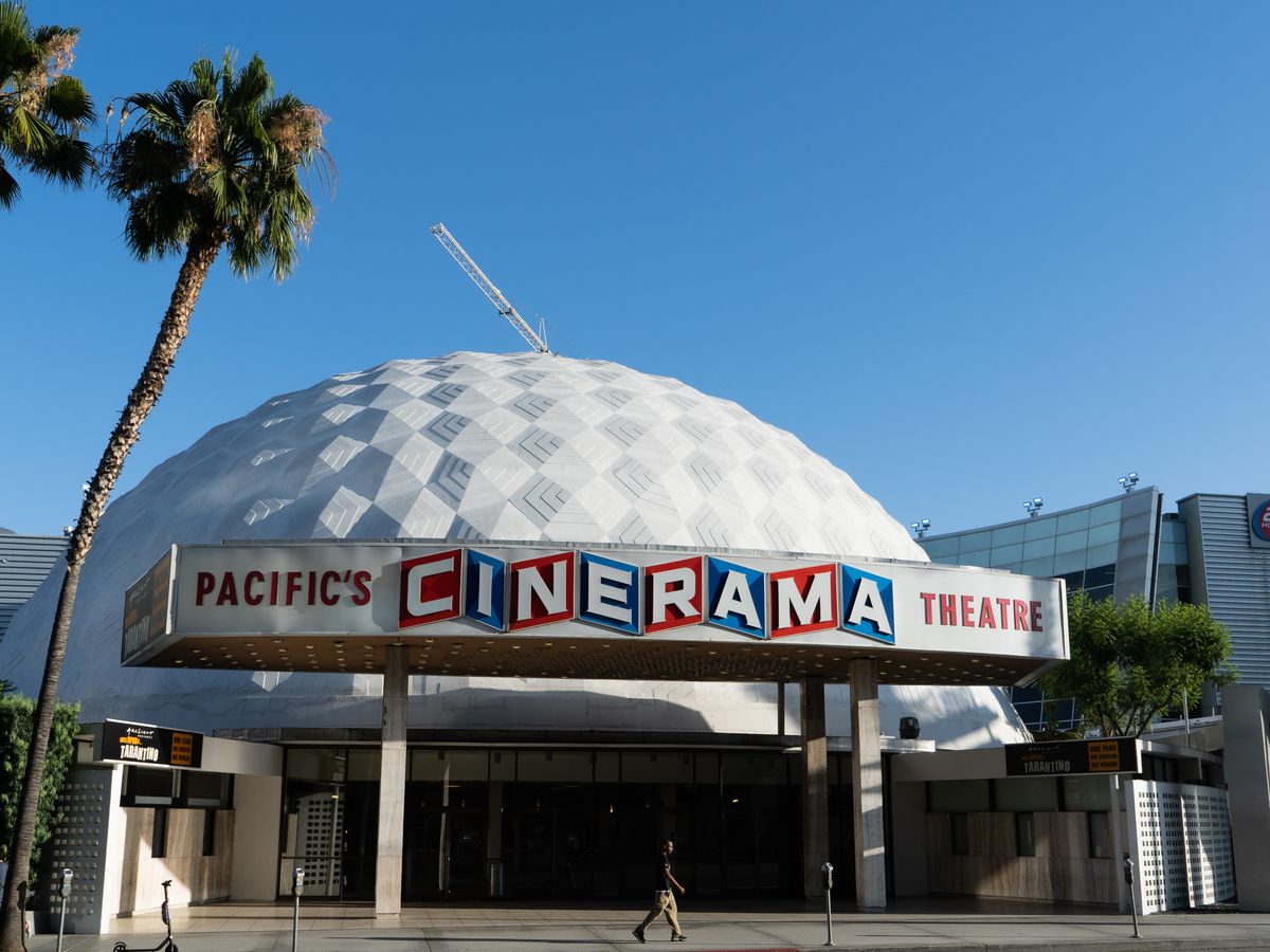 A white-colored dome against a light blue sky. In front is a sign reading “Pacific’s Cinerama Theatre”