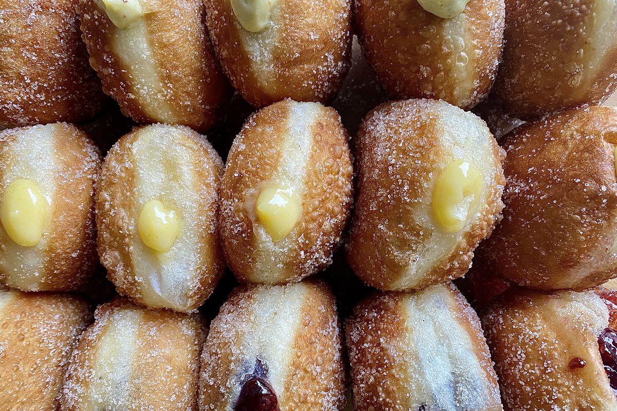 A row of filled doughnuts dotted with lemon curd and raspberry jam from Bomba