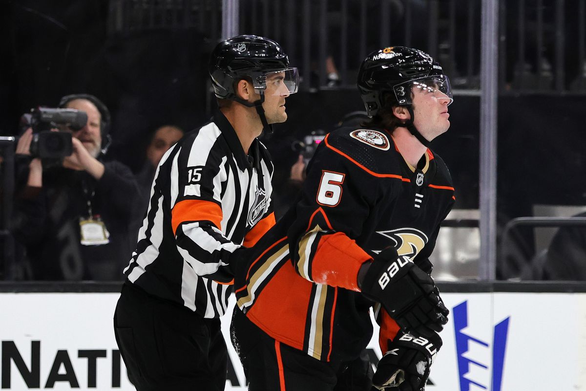Referee Jean Hebert helps Jamie Drysdale #6 of the Anaheim Ducks off the ice after he suffered an upper body injury in the second period of a game against the Vegas Golden Knights at T-Mobile Arena on October 28, 2022 in Las Vegas, Nevada. The Golden Knights defeated the Ducks 4-0.