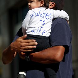 Bruce Klain holds his daughter, Linkyn Nizhoni Klain, as they gather with other demonstrators outside the Wells Fargo building in Salt Lake City on Monday, Oct. 31, 2016, to recognize the sovereign rights of the Standing Rock Sioux Tribe and stand in solidarity with the water protectors fighting against the Dakota Access Pipeline.