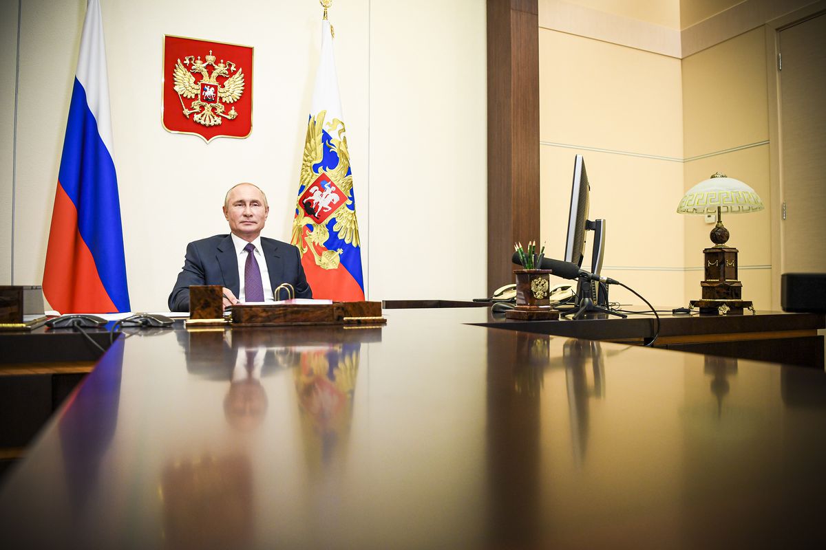 Russia’s President Vladimir Putin sitting at a desk during a videoconference meeting.