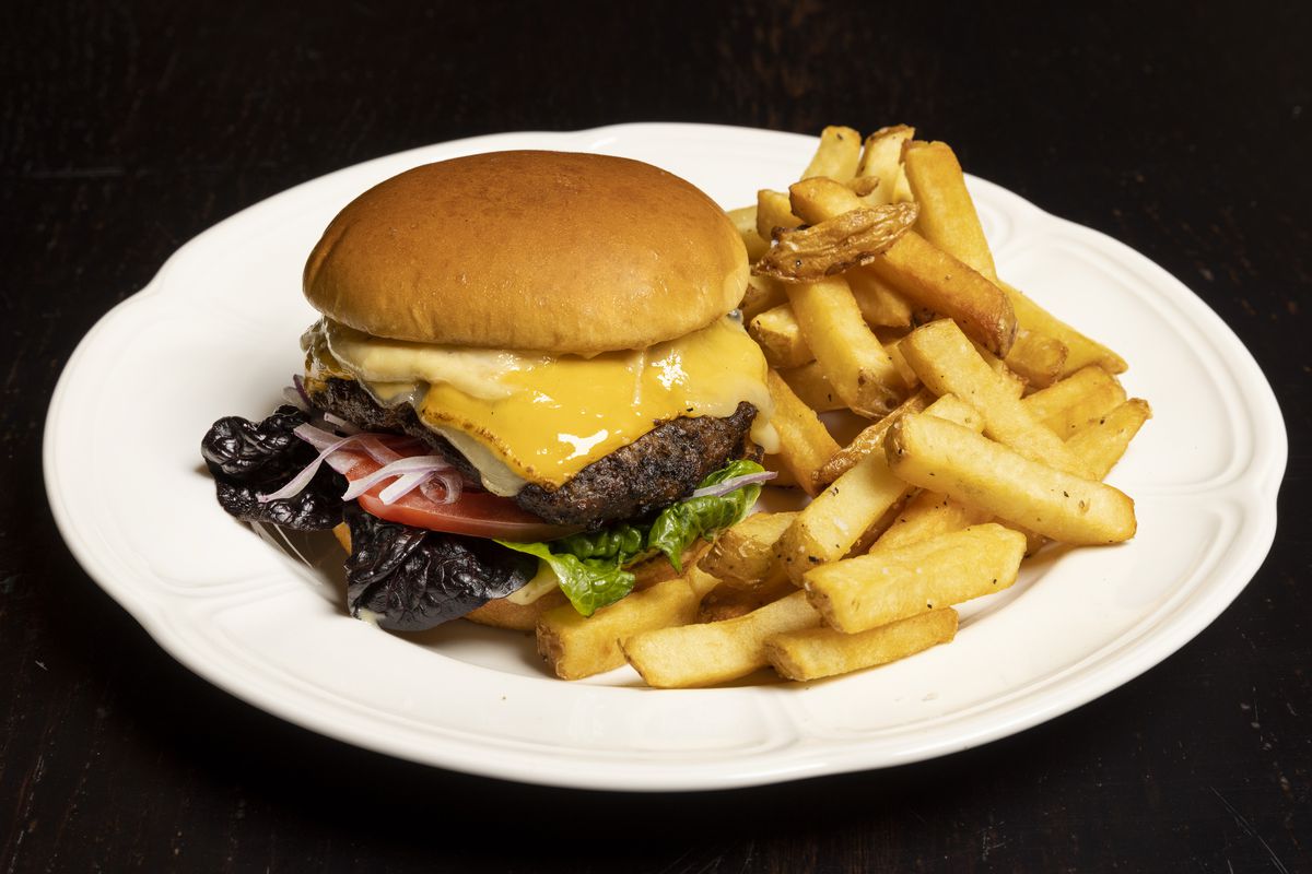 A large cheeseburger and fries on a round white plate.