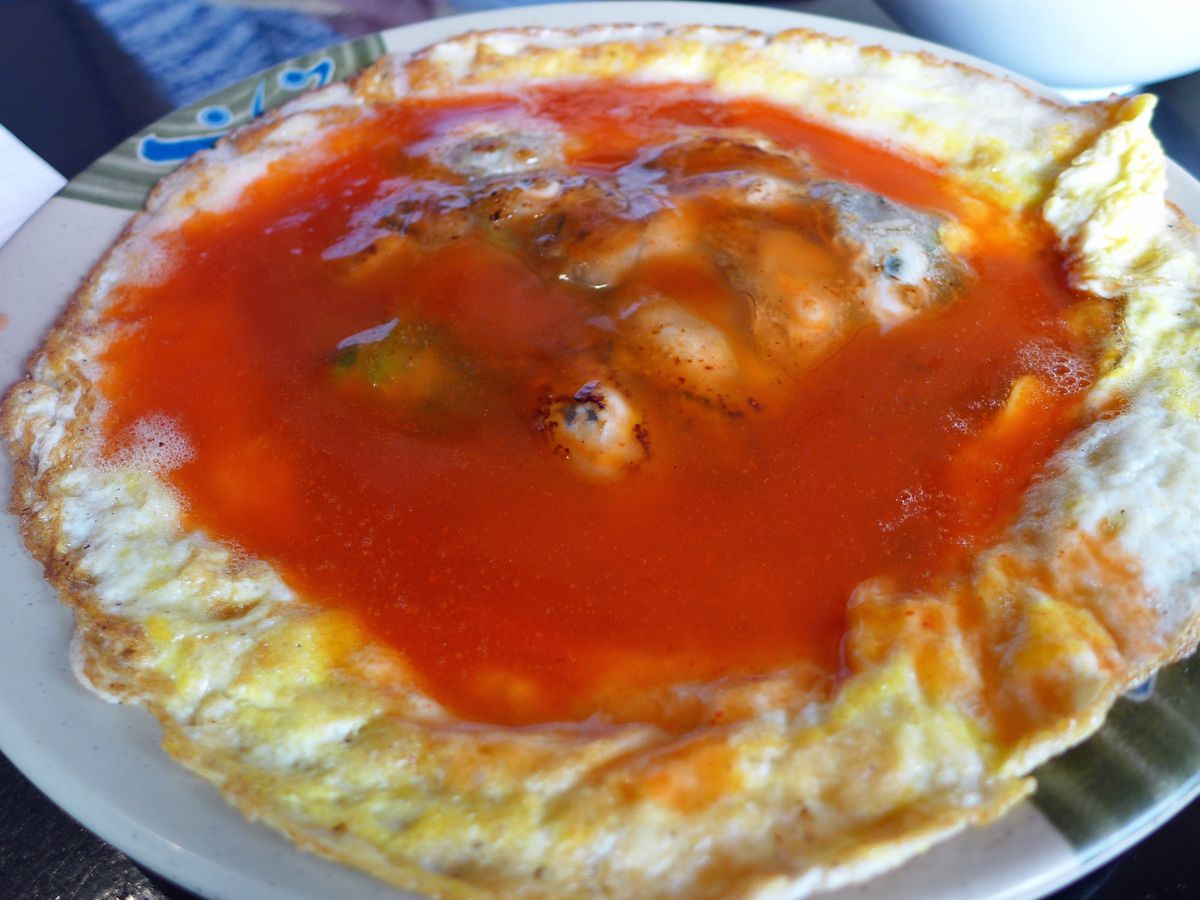 Oyster omelet at Happy Stony Noodle with red sauce pooled on top and oysters poking out.