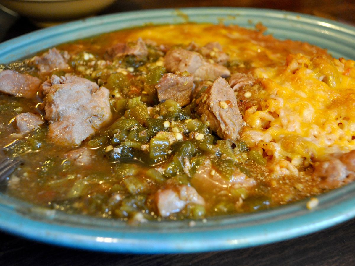 A plate of green chile with pork, rice, and beans